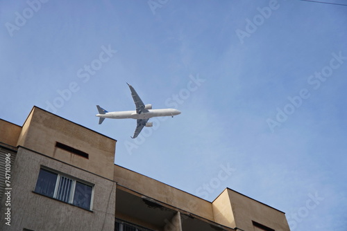 The plane flies over a residential multi-storey building.