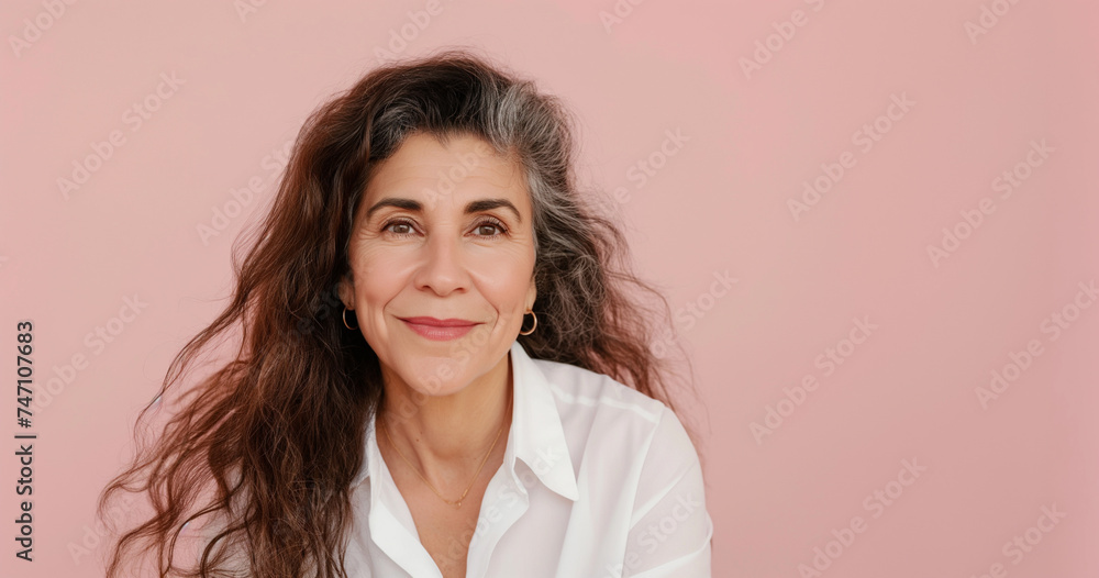 Studio portrait of mature smiling woman with graying hair, wearing white button up shirt, pink background Studio portrait of mature smiling woman with graying hair, wearing white button up shirt, pink background