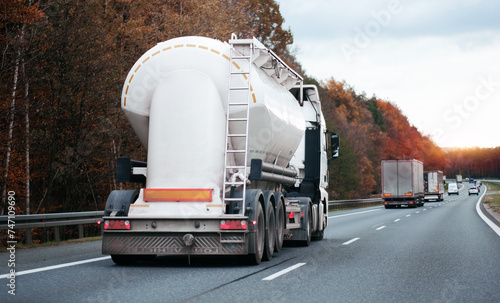 Petrol truck on highway hauling fossil oil refinery products. Fuel delivery transportation. Aviation fuel transportation. Compressed gas carrier truck rear view on a highway. Dairy products carrier	 photo
