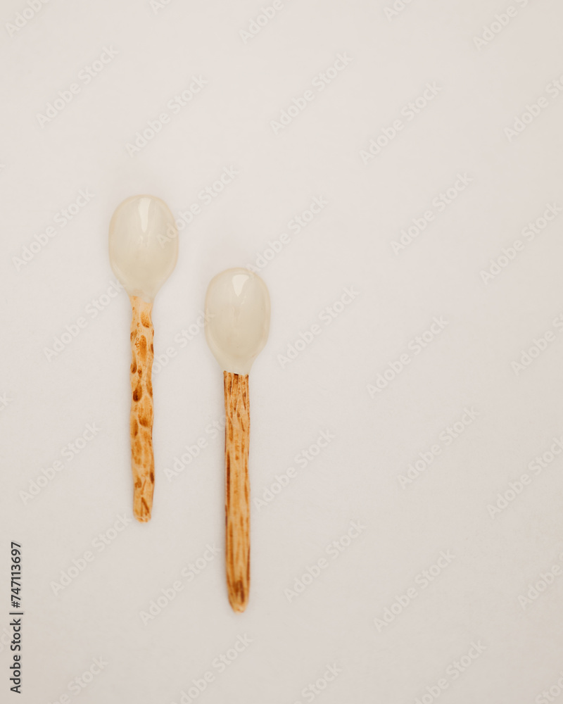 Two Unique Ceramic Spoons with Wooden Handles on a White Surface Two Unique Ceramic Spoons with Wooden Handles on a White Surface