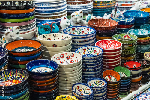 Variety of colorfully hand painted plates for sale at a market. Decorative ceramic plates on a shelf of a store