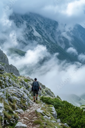 A lone hiker looking at a spectacular mountain view shrouded in mist and clouds