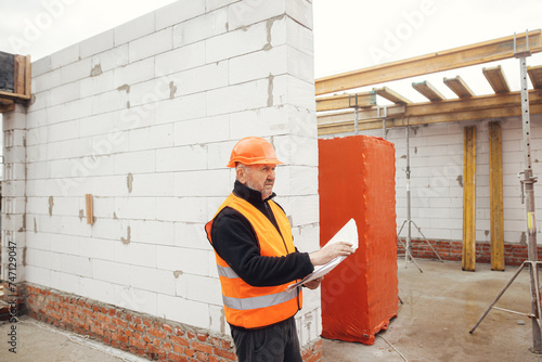 Wallpaper Mural Senior man engineer or construction worker in hardhat looking at blueprints at building new modern house. Male architect or contractor checking plans at construction site. Copy space Torontodigital.ca