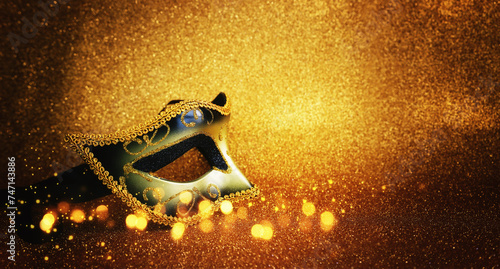 Photo of elegant Venetian mask over glitter gold background