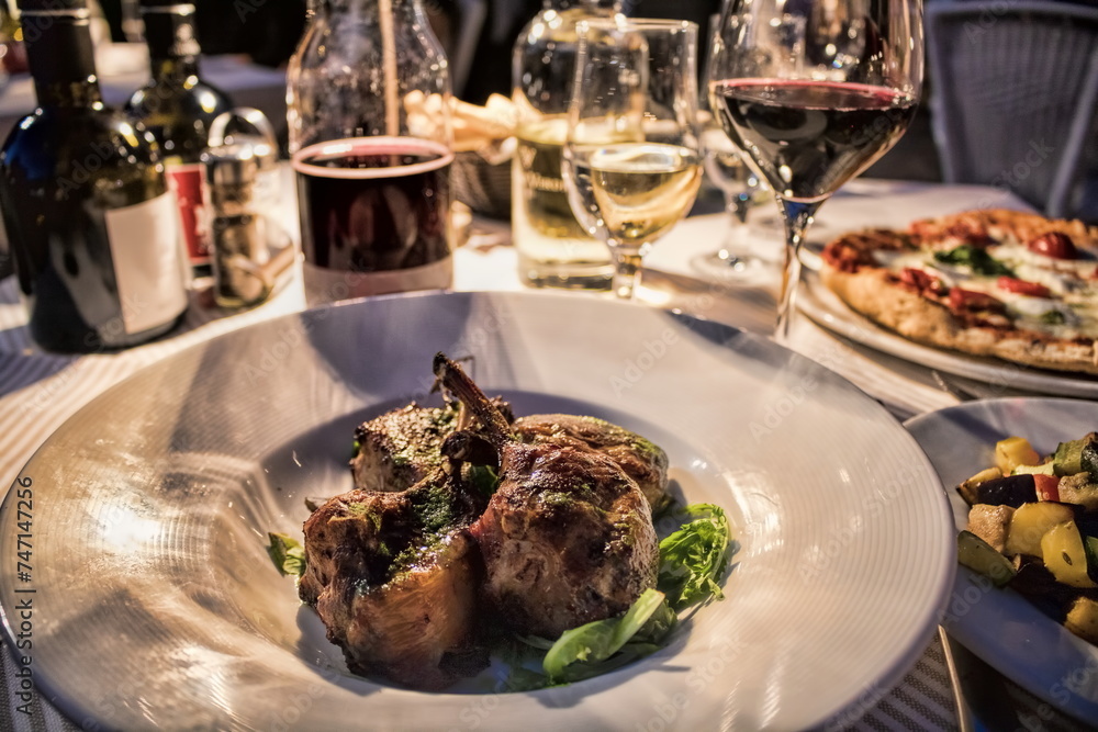 mantua, italien - italienisches abendessen mit pizza, kaninchenkeulen und wein