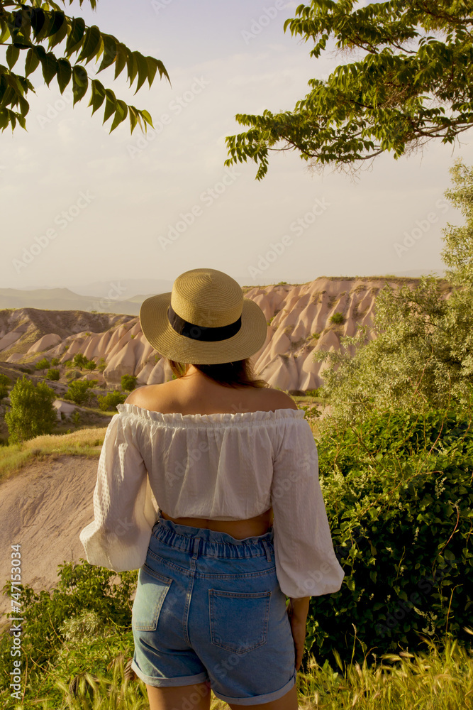 beautiful woman  in a white hat looking to the view of cappadocia, turkey