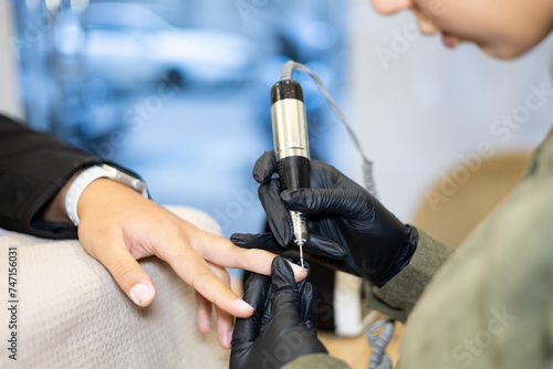 Manicurist making client's manicure removing nails polish. Professional manicure treatment in beauty salon. Hands hygiene and care in beauty industry.