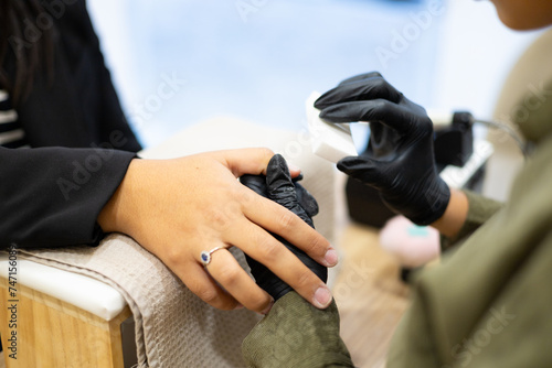 Manicurist making client's manicure removing nails polish. Professional manicure treatment in beauty salon. Hands hygiene and care in beauty industry.