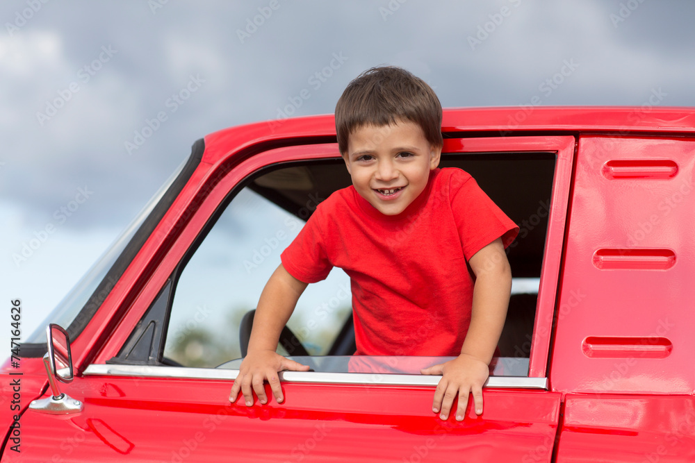 child boy waves from the cab of a red pickup truck with watermelons. banner. copy space.summer time in nature in the village child boy waves from the cab of a red pickup truck with watermelons. banner. copy space.summer time in nature in the village