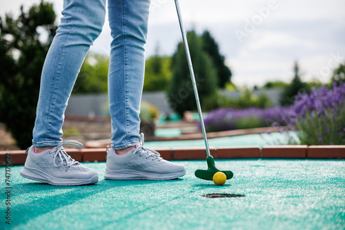 Golfer playing adventure or mini golf and trying putting ball into hole. Sports and leisure activity photo