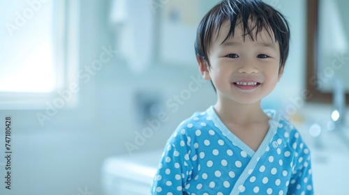Smiling child in blue polka dot pajamas in bathroom.