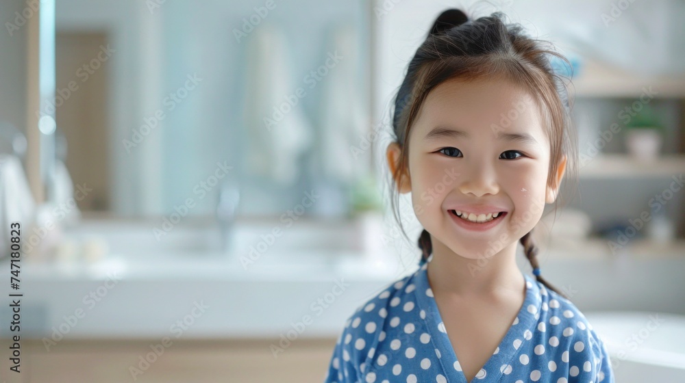Young girl with a radiant smile wearing a blue polka dot dress standing in a bathroom with a sink and mirror in the background. Young girl with a radiant smile wearing a blue polka dot dress standing in a bathroom with a sink and mirror in the background.