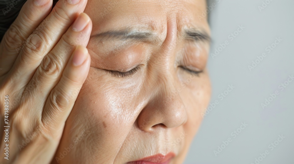 Obraz premium A woman with her eyes closed resting her head on her hand showing signs of stress or exhaustion.