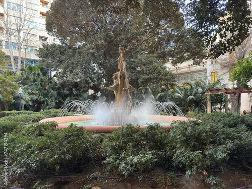Water fountain surrounded by vegetation in Gabriel Miro urban square in downtown Alicante, Spain.