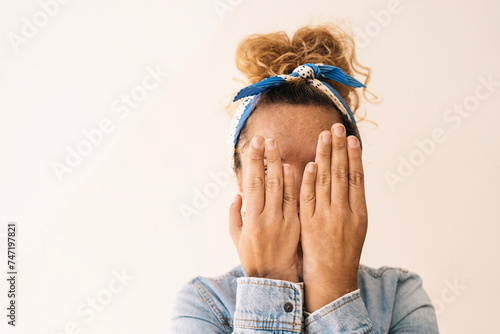 A woman conceals her face with her hands, showcasing a unique hand structure post-surgery with missing thumbs, set against a simple background photo