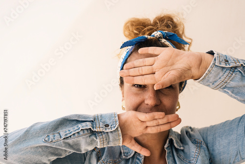 A woman in a denim jacket and headband makes a playful gesture by covering their face with a hand that has undergone surgery for thumb absence photo