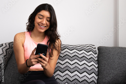 Smiling young woman enjoying technology on sofa photo