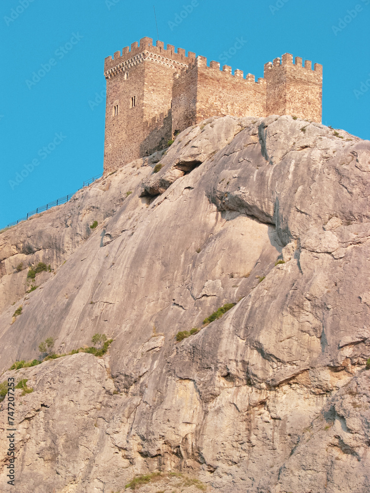 A medieval fortress on a stone rock against the background of a clear blue sky. A medieval fortress on a stone rock against the background of a clear blue sky.