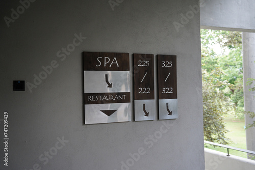 spa and restaurant wooden and steel signs on a wall with room numbers.   