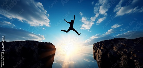 A daring man is seen in mid-leap, vaulting off the edge of a high cliff with his body extending towards the vast open sky. photo