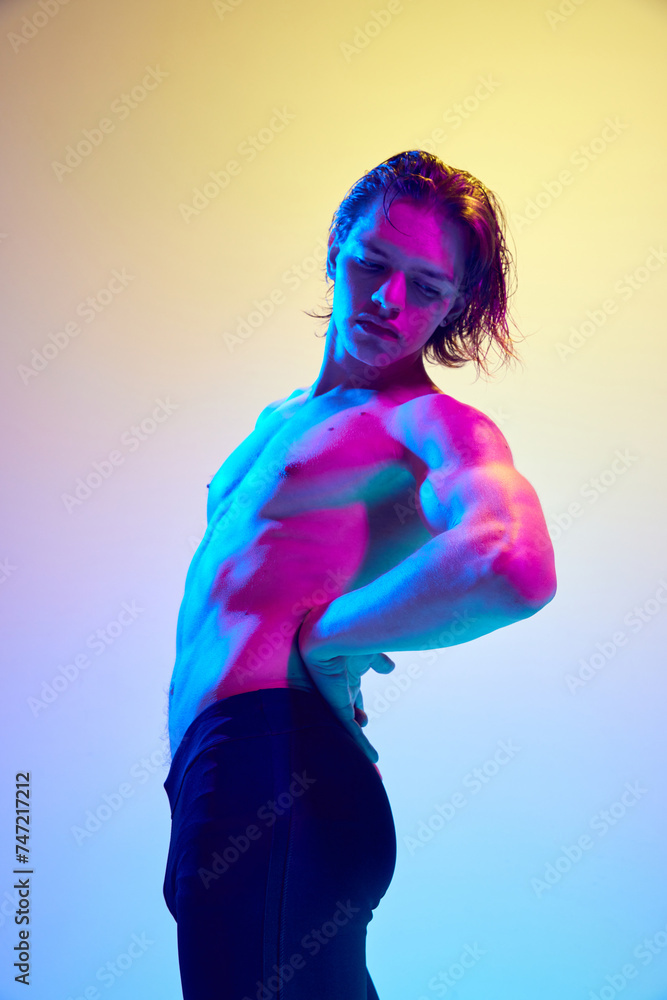 Side view portrait of young man with wet hair posing showing his perfect body in vibrant neon light against gradient background. Concept of natural beauty people, fitness, male health, masculinity. Side view portrait of young man with wet hair posing showing his perfect body in vibrant neon light against gradient background. Concept of natural beauty people, fitness, male health, masculinity.