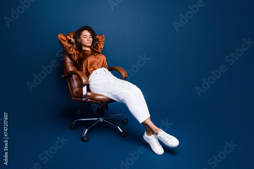 Full length photo of lovely young lady sit office break have rest wear trendy brown satin formalwear isolated on dark blue color background