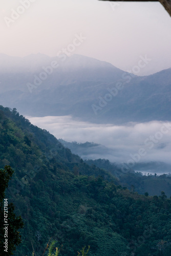 Misty mountain landscape, clear blue cloudless sky and layers of hills. Cold mood.