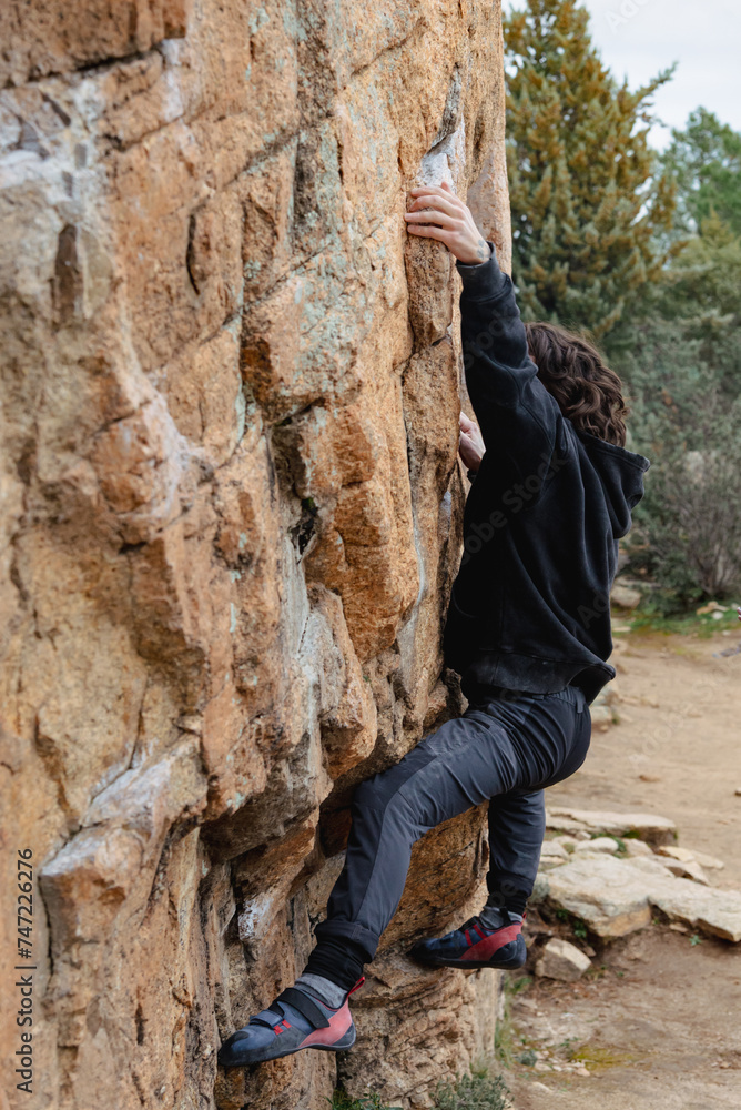 © ADDICTIVE STOCK - Focused on the ascent, a climber tackles a steep rock face with precision and agility, surrounded by a natural landscape