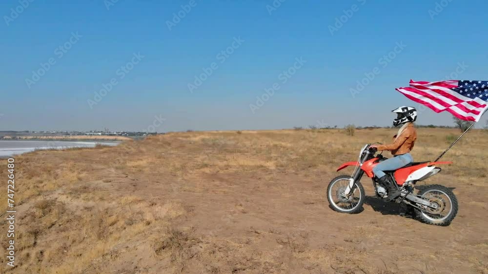 Biker on a sports motorcycle against the background of the USA flag, off-road motocross in the USA. Biker on a sports motorcycle against the background of the USA flag, off-road motocross in the USA.