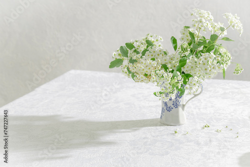 Beautiful spring white flowers in the rastic vase on the table. Whaite tablecloth and whate bouquet photo