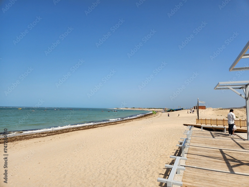 Fototapeta premium Dwarka, Gujarat India - Feb 21 2024: Shivraj Beach (Blue flag beach) - Long, flat white-sand beach with rocky outcrops and calm waves, plus wooden, grass-roofed umbrellas in Gujrat.