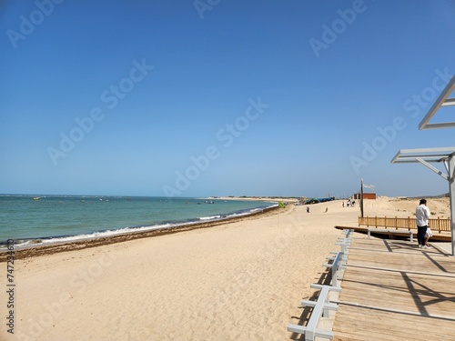 Dwarka, Gujarat India - Feb 21 2024: Shivraj Beach (Blue flag beach) - Long, flat white-sand beach with rocky outcrops and calm waves, plus wooden, grass-roofed umbrellas in Gujrat.