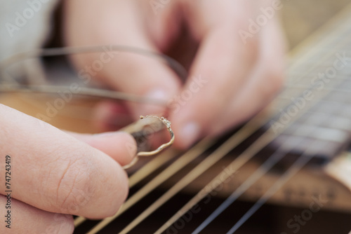 Macro shot of torm guitar string in hands of a guitarist. Changing strings in the guitar