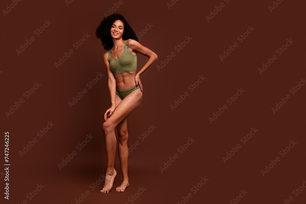No retouch full length photo of charming girl strong muscular athletic body empty space isolated on brown color background No retouch full length photo of charming girl strong muscular athletic body empty space isolated on brown color background