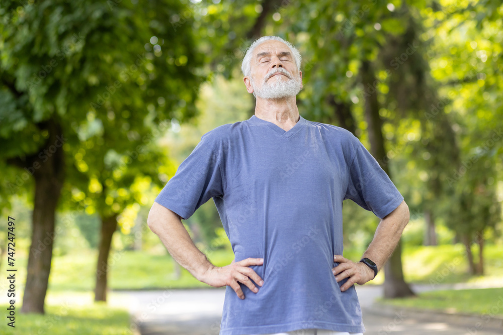 Senior man taking a deep breath during outdoor exercise in a sunny park Senior man taking a deep breath during outdoor exercise in a sunny park
