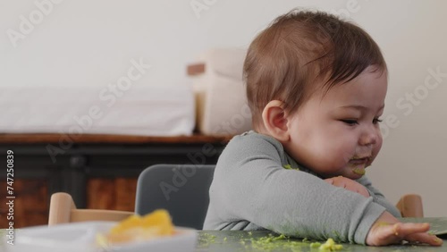 Baby boy with a spoonful of avocado refuses an applesauce packet