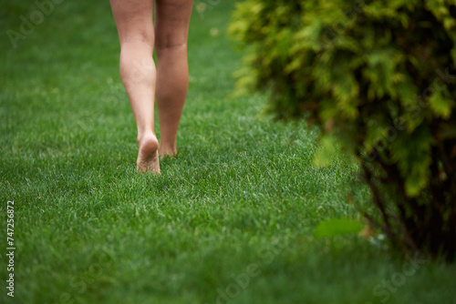 Adult woman walking barefoot on the grass in the park