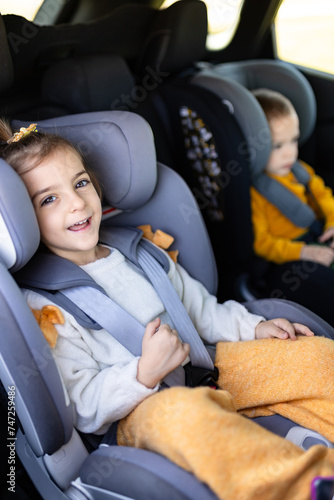 Side view portrait of young girl in car seat traveling with her brother.