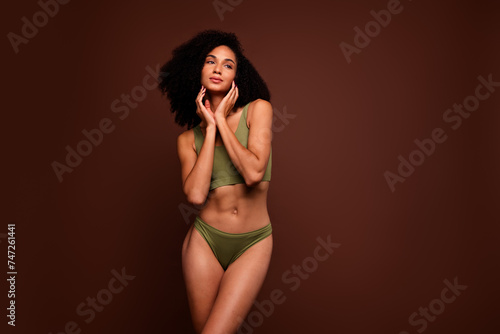 No filter studio photo of shiny thoughtful woman wear lingerie applying cream looking empty space isolated brown color background © deagreez