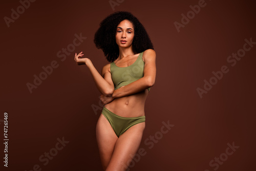 No filter photo of gorgeous nice girl slim strong figure advertising sportive underwear isolated on brown color background