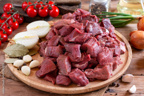 Raw sliced beef or lamb meat, spices, herbs on a wooden background. Goulash. Raw organic meat.