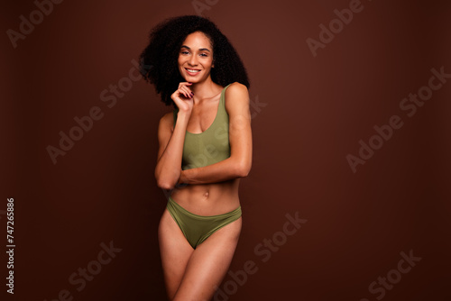Studio no retouch photo of confident cute lady dressed lingerie arm chin empty space isolated brown color background © deagreez
