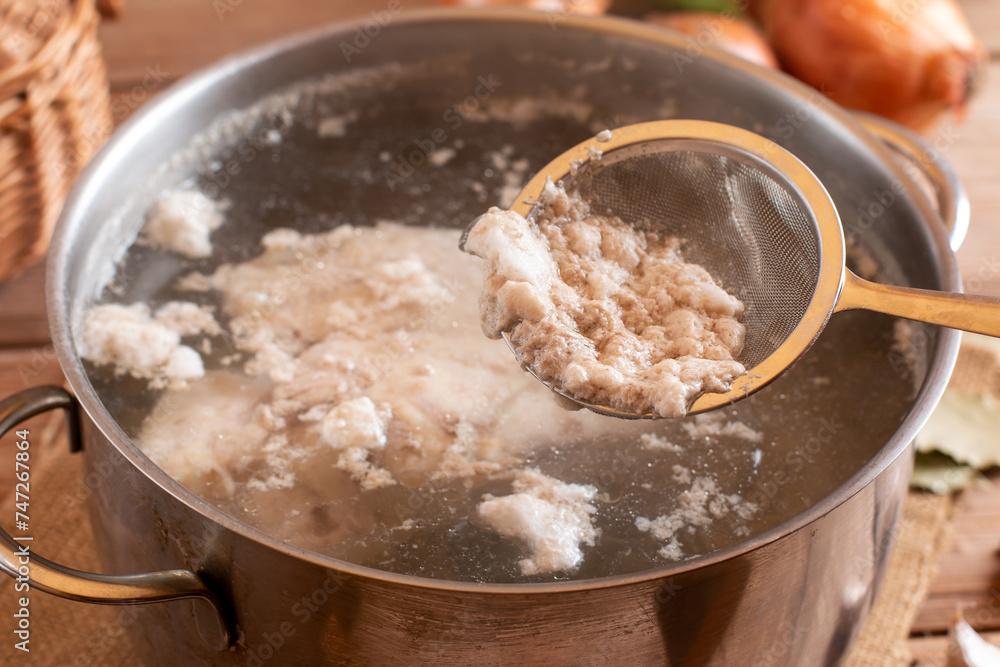 Metal skimmer and meat broth foam. Dirty kitchen utensils in a metal bowl. Cooking a family dinner. Selective focus. Metal skimmer and meat broth foam. Dirty kitchen utensils in a metal bowl. Cooking a family dinner. Selective focus.