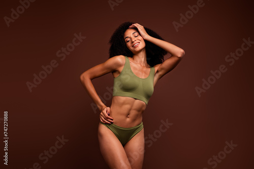 No filter photo cheerful beautiful slim sporty healthy woman in khaki fitness bikini posing isolated on brown color background © deagreez