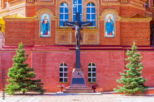 Russia Saraktash August 20, 2022: Trinity Simeon's Convent of Mercy. Statue of the crucified Christ on the cross near the wall of the Cathedral of the Life-Giving Trinity. Orenburg region.