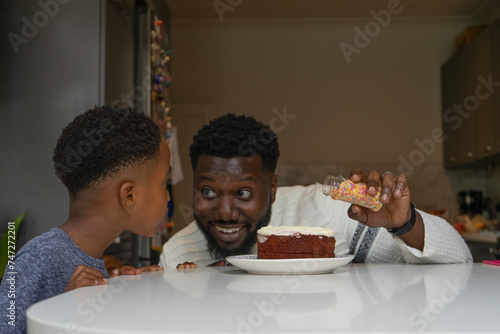 Father and son (6-7) preparing birthday cake