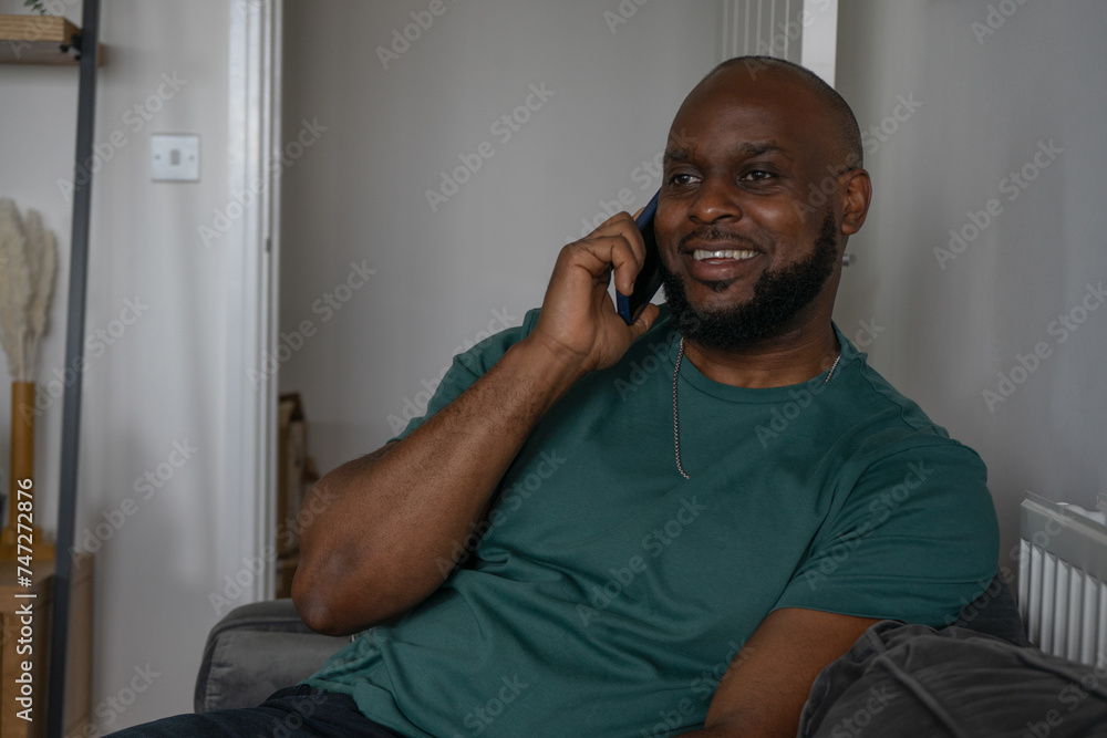 Smiling man talking on smart phone at home Smiling man talking on smart phone at home