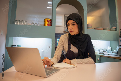 Female cafe owner working on laptop