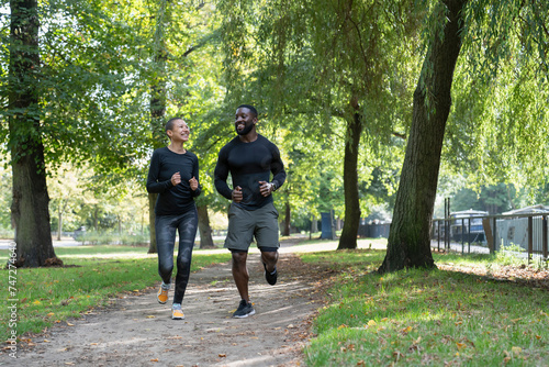 Smiling man and woman jogging in park photo