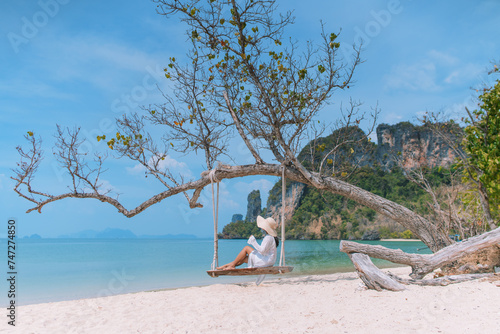 Young woman sitting on a swing on the beach © Kanbokeh